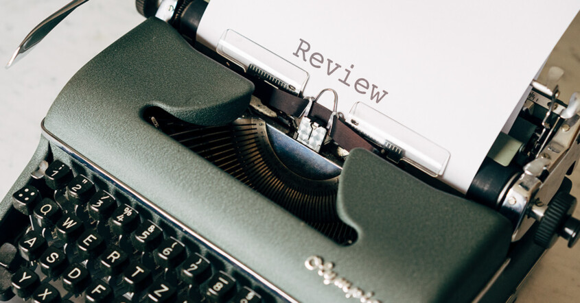 Typewriter showing a piece of paper with the typed word "review"
